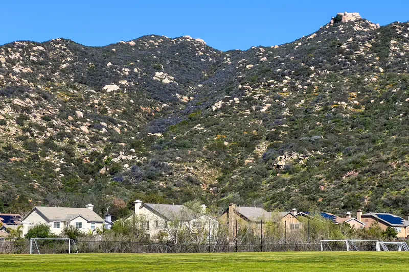 Rocky chaparral hillside rising steeply above a row of homes in Escondido