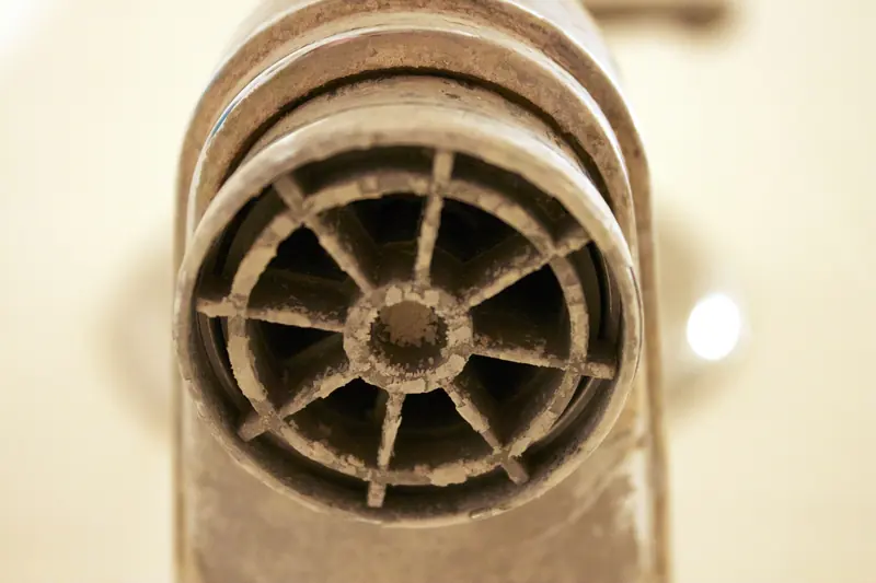 Faucet aerator with its outlet crusted in white limescale, the buildup a softener is bought to prevent